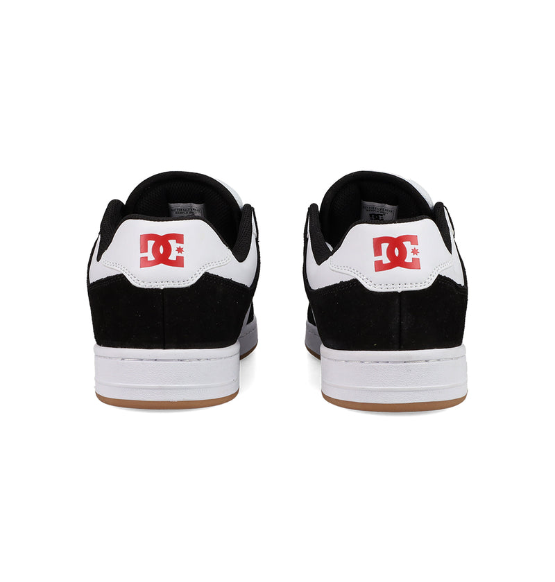 The Men's Manteca 4 Shoes by DC Shoes feature a classic black and white design, visible red DC Shoes logos on the heels, white midsoles, and gum-colored outsoles, shown here from the back.