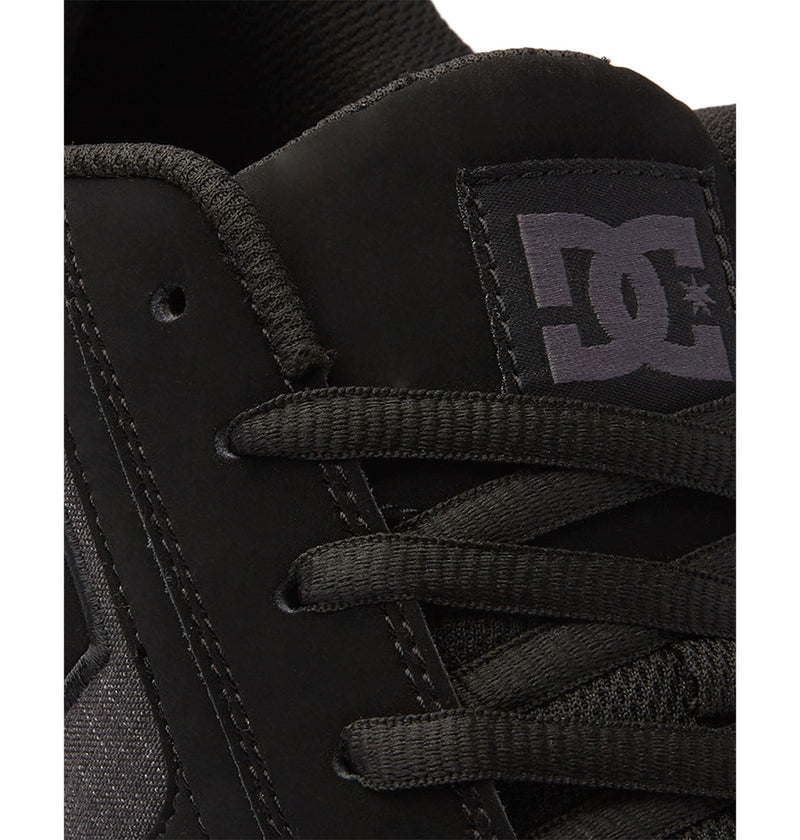 Close-up of a black DC Shoes Men's Net sneaker highlighting the laces, eyelets, and tongue with the white "DC" logo. Made with suede-like and textured durable fabrics for long-lasting style and comfort.