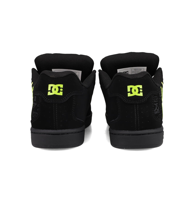 A pair of Men's Net Shoes by DC Shoes in black, seen from the back with neon yellow DC branding on the heels, padded black collars, and a durable, puffy skate sneaker design.