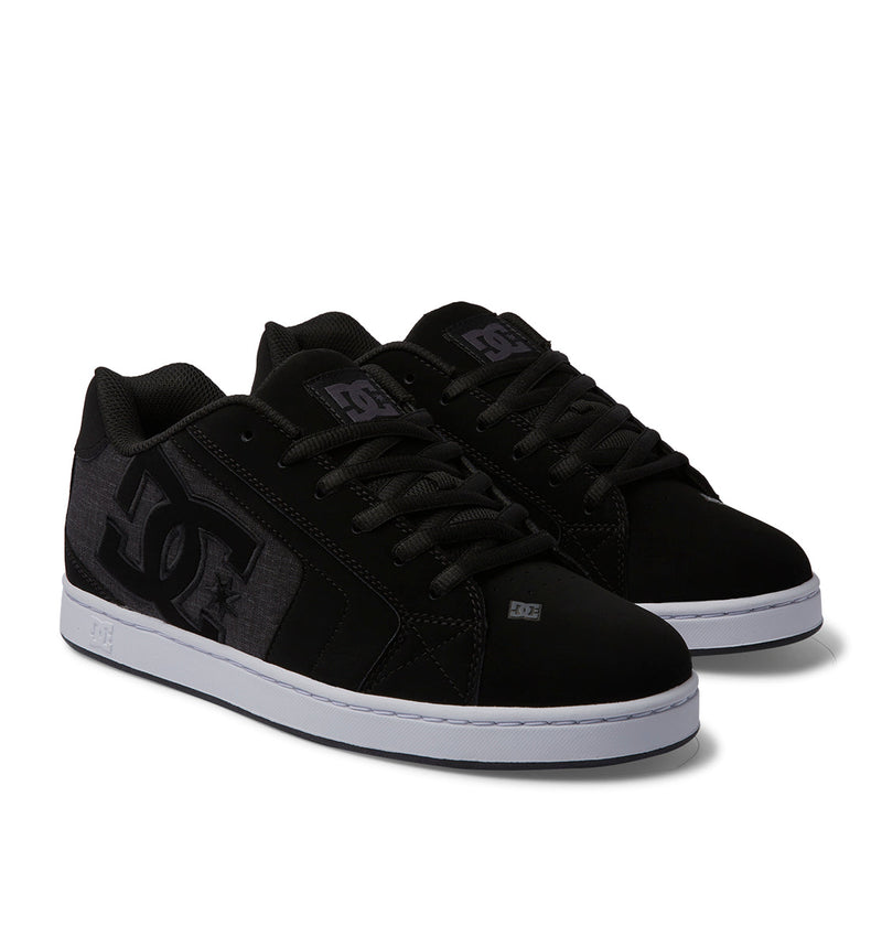 A pair of Men's Net Shoes by DC Shoes, featuring puffy black sneaker styling with black laces, a bold DC logo on the side, and white rubber soles. Durable construction. Both shoes are displayed side by side on a white background.