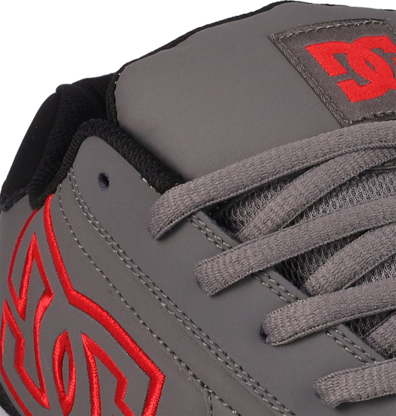 Close-up of the DC Shoes Men's Net sneaker in gray with gray laces, black trim, and a bold red embroidered DC logo on the side and tongue, crafted from durable materials.