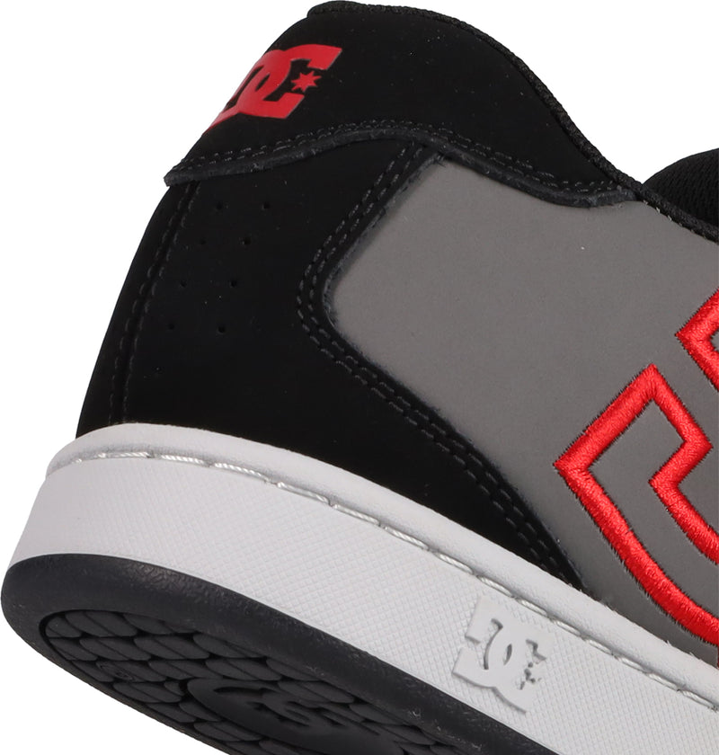 Close-up of the heel and side of the DC Shoes Men's Net Shoes, a puffy sneaker in black, gray, and white with red stitched DC branding and a textured black sole.