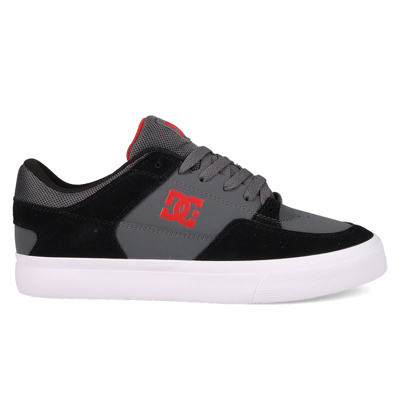 The DC Shoes Men's Onyx Shoes are black and gray skate shoes with a minimal silhouette, white sole, red side logo, gray laces, and a red tongue accent, shown in a side profile view.
