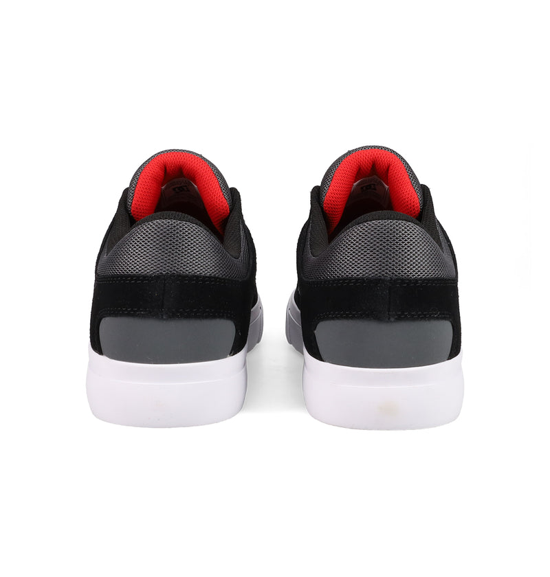 DC Shoes Men's Onyx Shoes in black and gray with white soles and red inner lining are displayed from the back, highlighting their minimal silhouette, against a plain white background.