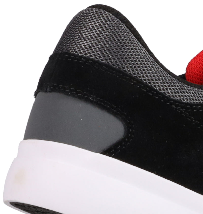 Close-up of the heel and ankle area of the Men's Onyx Shoes by DC Shoes in black and gray, showing mesh, suede, synthetic materials, a white sole, minimal silhouette, and a touch of red fabric near the top.