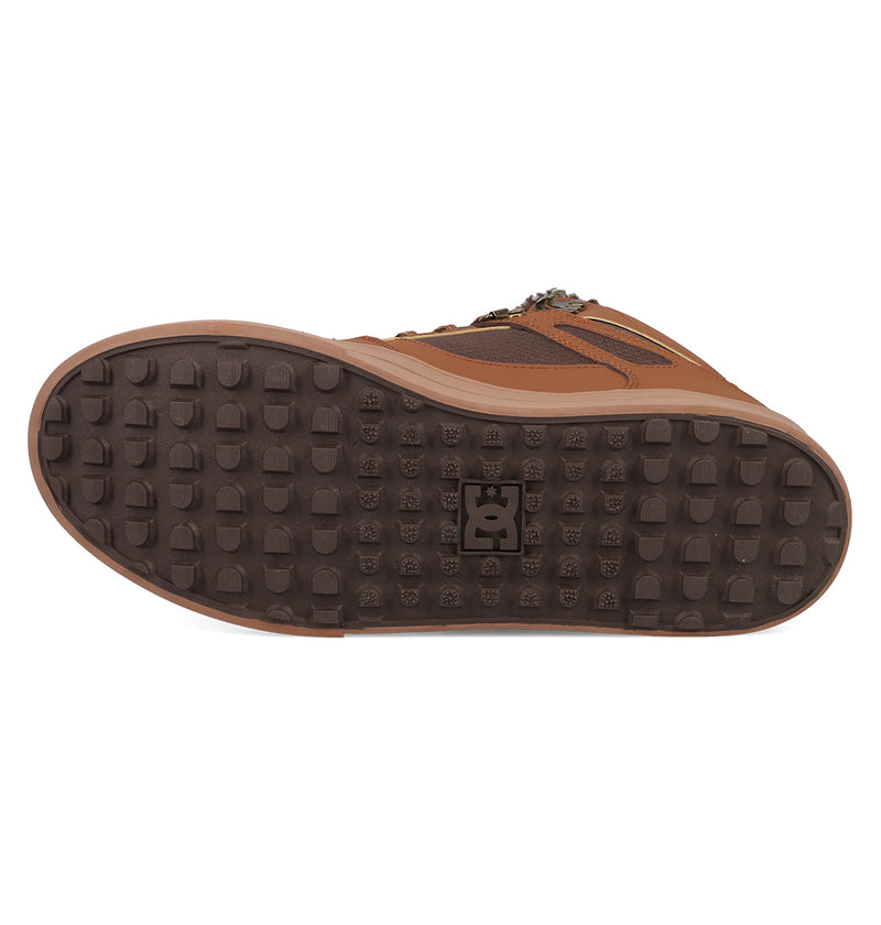 The image displays the brown vulcanized outsole of the DC Shoes Men's Pure High Top WC Shoes with a textured square tread and central DC logo. The upper features brown and tan leather, offering a classic style.