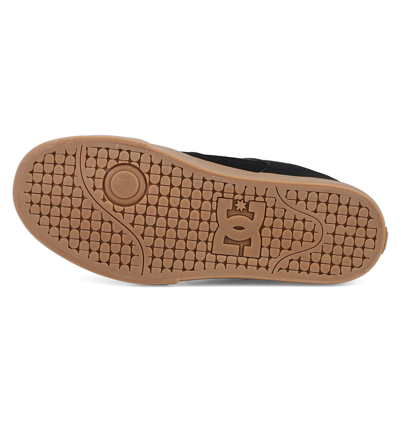 The image shows the brown rubber sole of the DC Shoes Men's Pure Shoe, featuring a textured hexagonal tread pattern and a central logo, highlighting its durable construction for comfortable wear.
