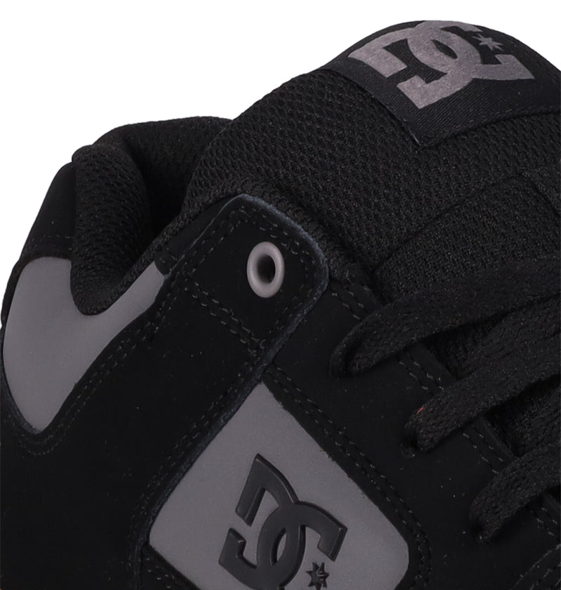 Close-up of DC Shoes Men's Pure Shoes in black, featuring a gray DC logo on the side and tongue, black laces, metallic eyelets, and a padded collar for comfort.