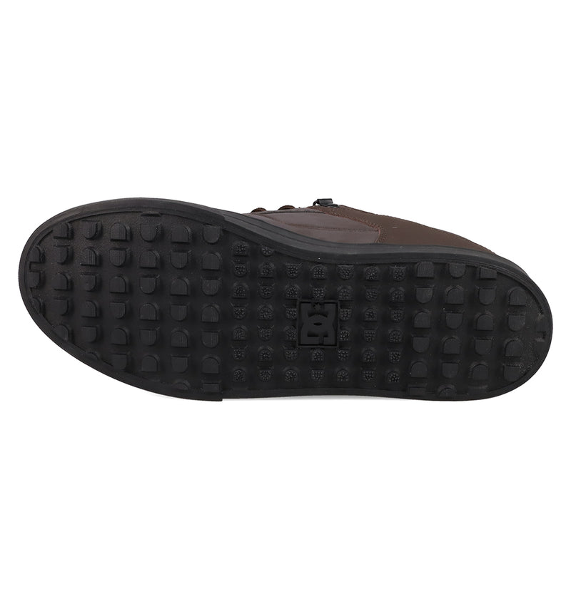 The image shows the bottom view of the Men's Pure Shoes by DC Shoes, featuring a black rubber sole with raised square treads in a grid pattern and a logo at the center, underscoring its versatile design.