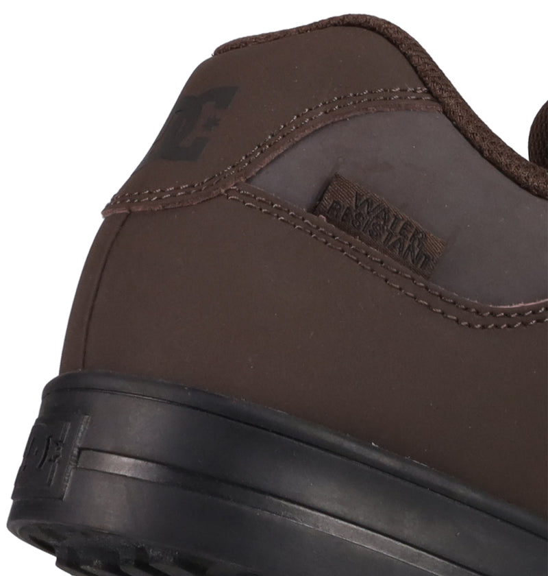 Close-up of the heel and side of DC Shoes Men's Pure Shoes in brown with a black sole, featuring WATER RESISTANT and the DC logo embossed on the leather near the heel for comfort and versatility.