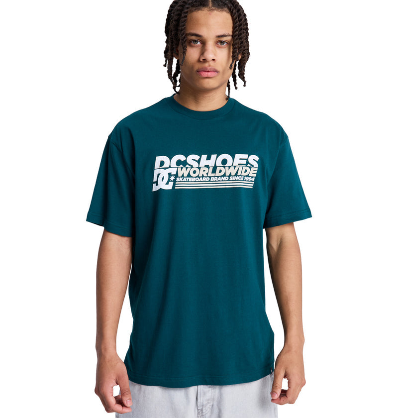 A young person with braided hair wears a teal Reebok Queltra Lhss t-shirt and stands facing forward against a plain white background.