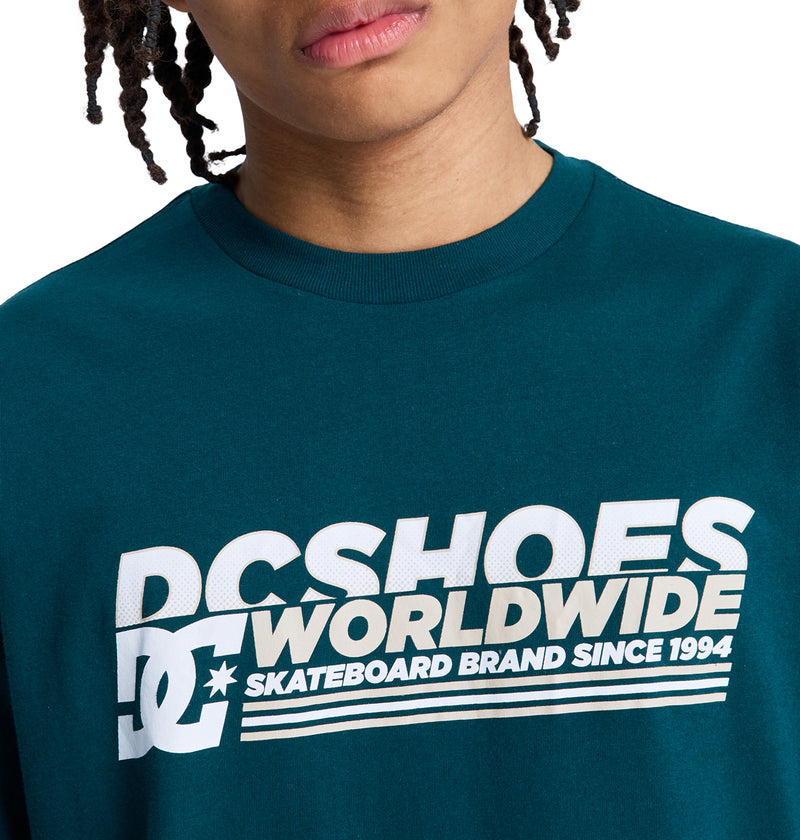 A person wearing a teal Reebok Queltra Lhss t-shirt; only the lower half of their face and upper torso are visible.