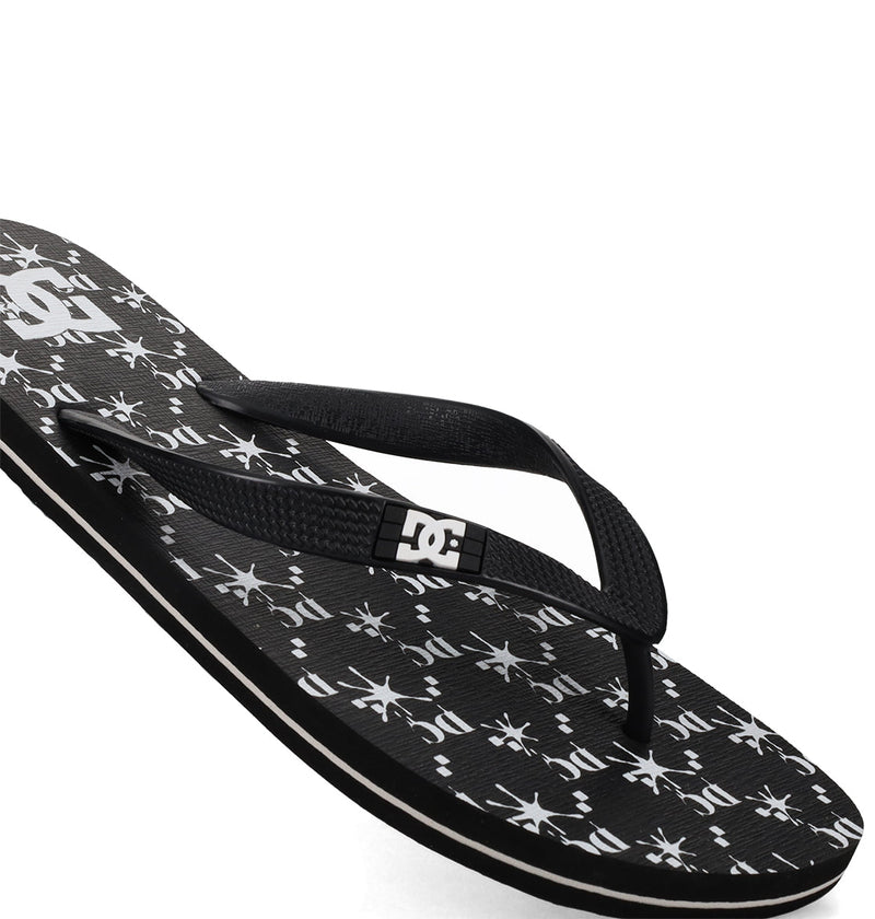The Men's Spray Graffik Slides by DC Shoes feature a black slip-on design with a white DC logo on the strap and a patterned footbed with repeating DC logos and starbursts—ideal for relaxing after skating.