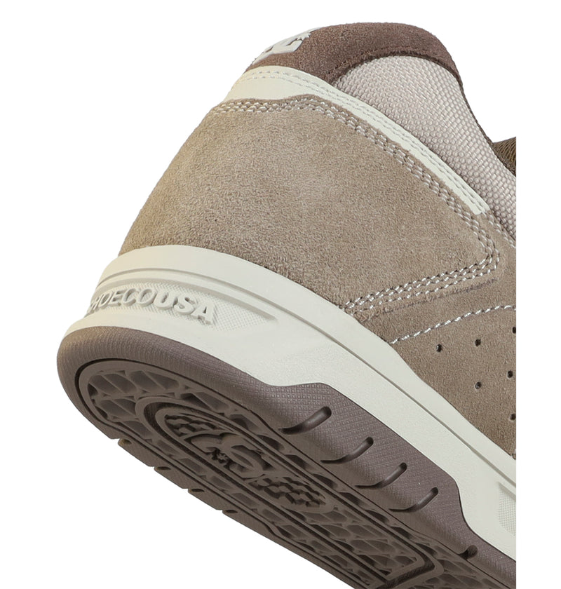 Close-up of the heel and sole of the DC Shoes Men's Stag sneaker, featuring beige and brown suede and mesh textures, visible stitching, embossed DC branding near the midsole, and a durable cupsole for lasting wear.