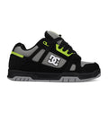 Black sneaker with green accents and a visible brand logo on a white background