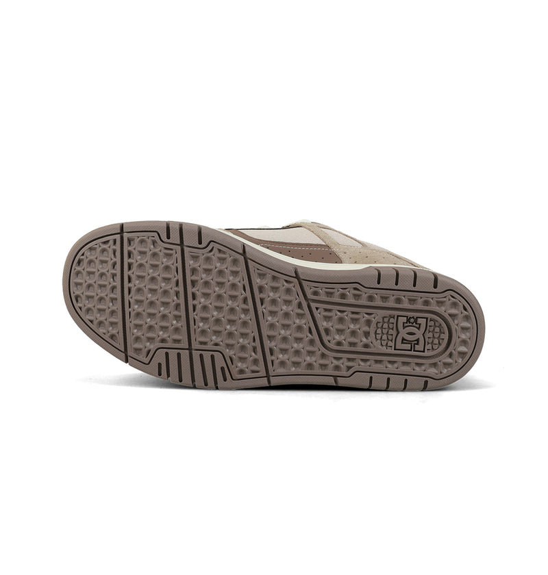 The Men's Stag Shoes by DC Shoes are shown from the bottom, highlighting their durable beige and brown cupsole with geometric patterns and a DC Shoes logo near the heel.