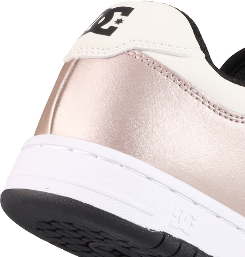 Close-up of the heel on DC Shoes Women's Manteca 4 Shoes, featuring a metallic rose gold side, white heel tab with a black DC logo and star, plus a white sole and textured black bottom.